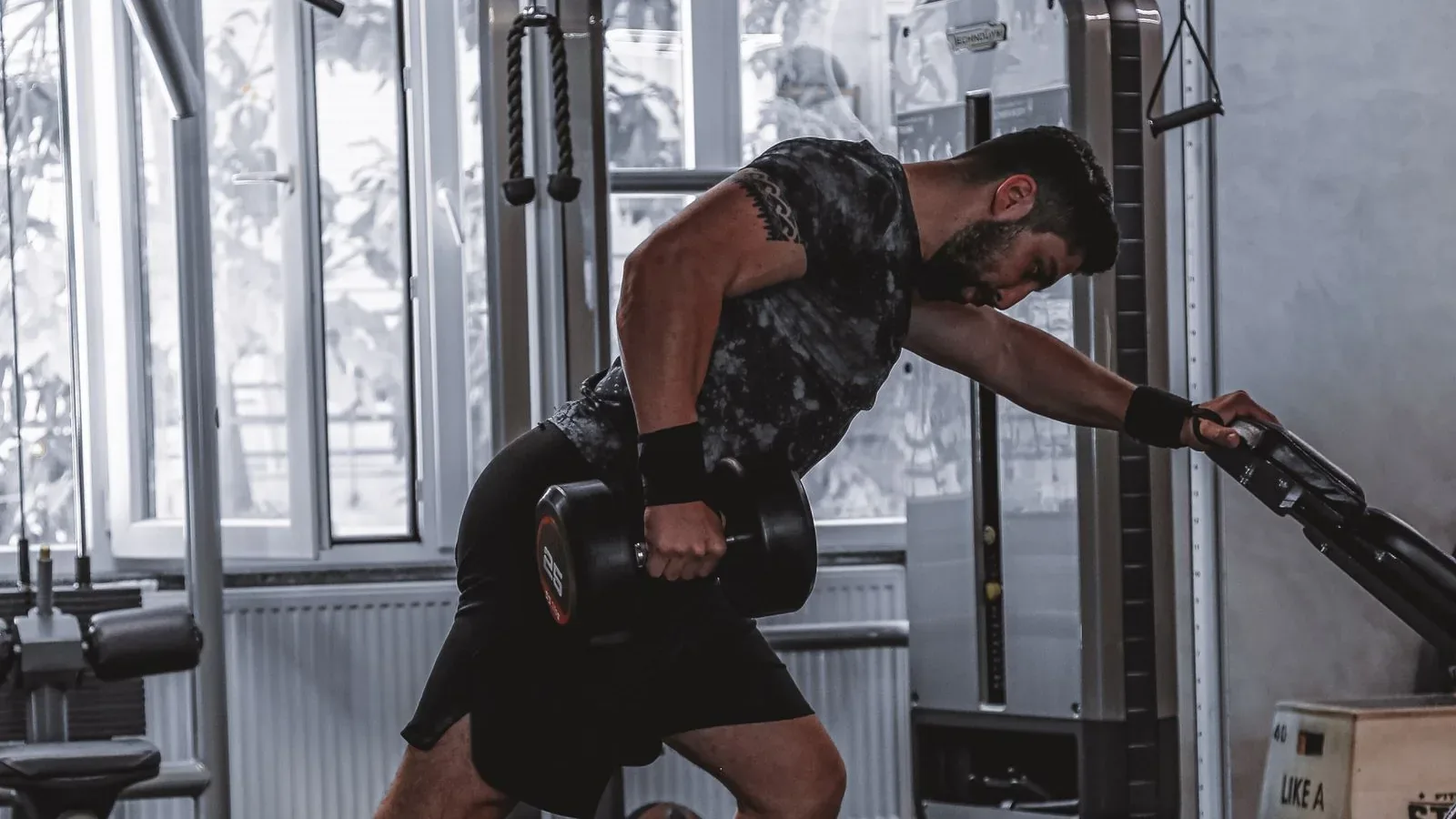 Man performing a one-arm dumbbell row with an adjustable dumbbell in a home gym